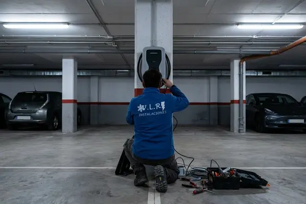 Electricista de VLR Instalaciones instalando un cargador de coche eléctrico en un garaje comunitario