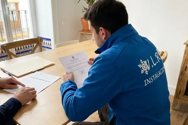 Electricista de VLR Instalaciones repasando el presupuesto y el certificado de instalación con un cliente en la mesa de su casa