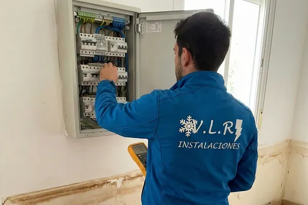 Técnico de VLR Instalaciones revisando cuadro eléctrico con marcas de inundación en la pared