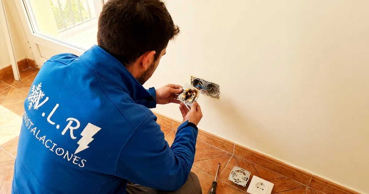 VLR Instalaciones electrician examining the burnt mechanism of a socket he has just removed from the wall