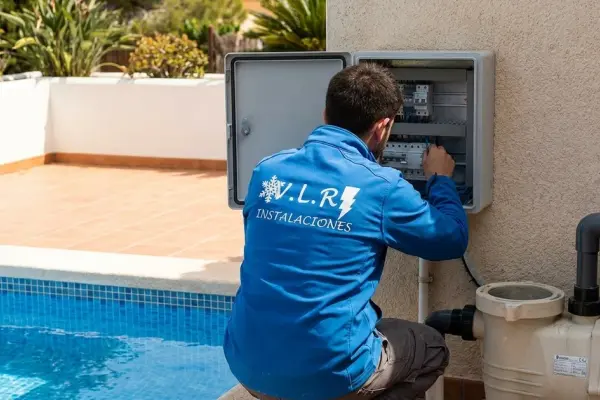 Electricista de VLR Instalaciones trabajando en el cuadro estanco junto a la depuradora de una piscina