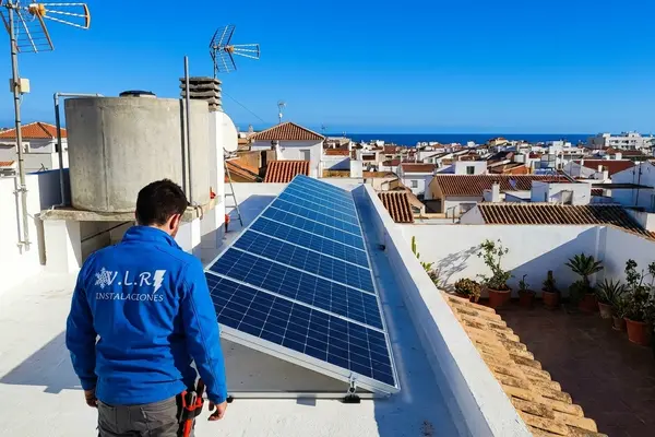 Electricista de VLR Instalaciones revisando placas solares instaladas en la azotea de un edificio de viviendas en la costa de Málaga